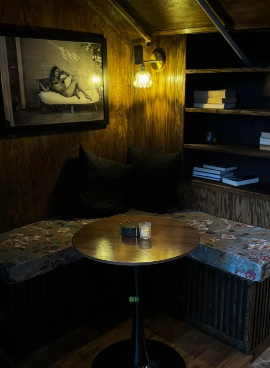 A candlelit corner booth with floral cushions and a bookshelf inside Lee's lounge