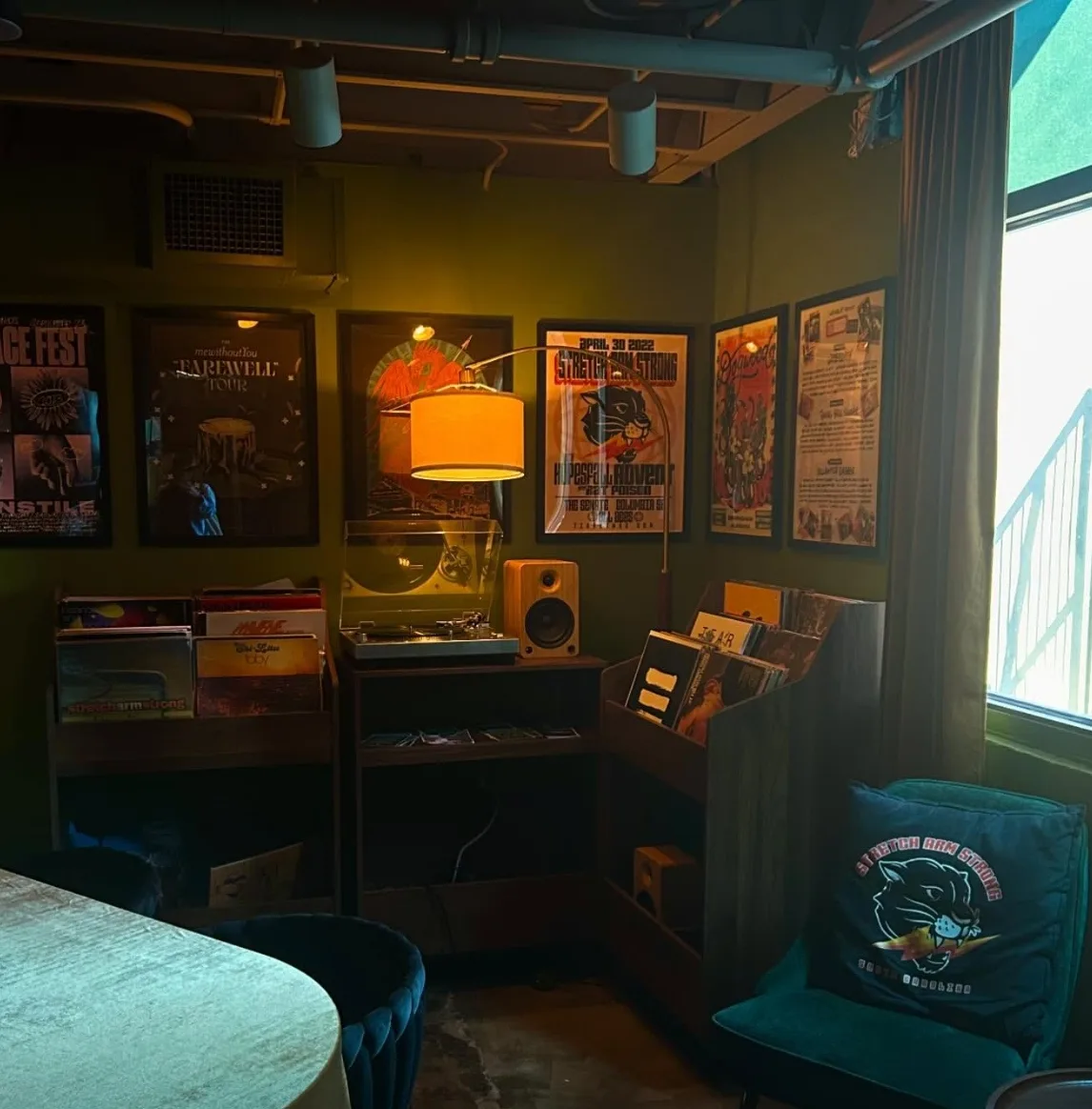 The listening room at Lee's with olive walls, vinyl crates and framed concert posters