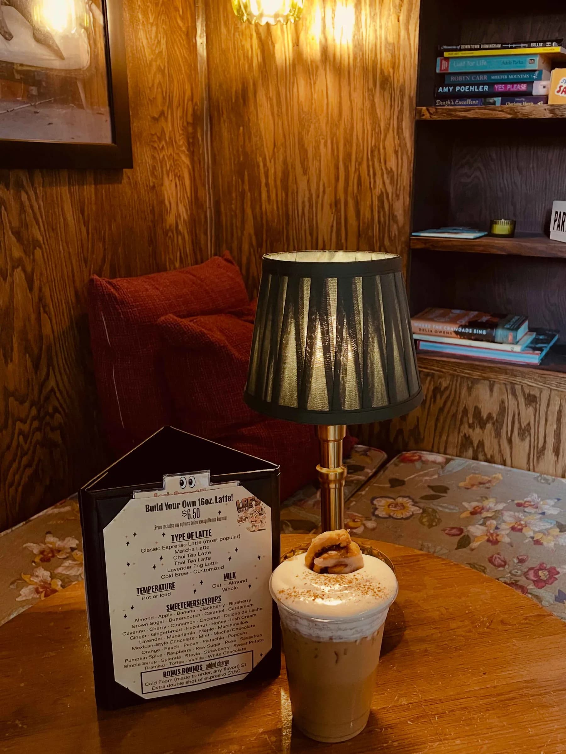 An iced latte with cold foam and a mini cinnamon roll beside Lee's Build Your Own Latte menu