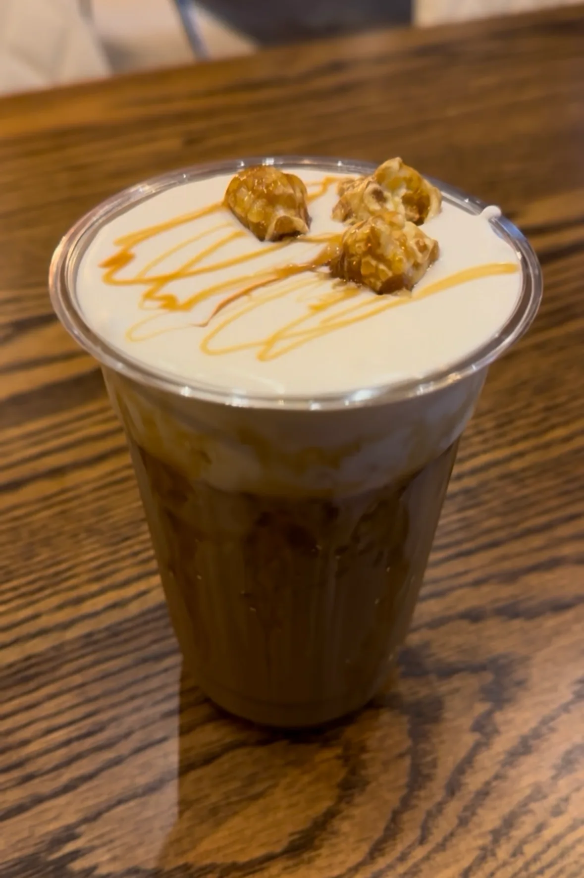 An iced latte topped with caramel drizzle and caramel popcorn