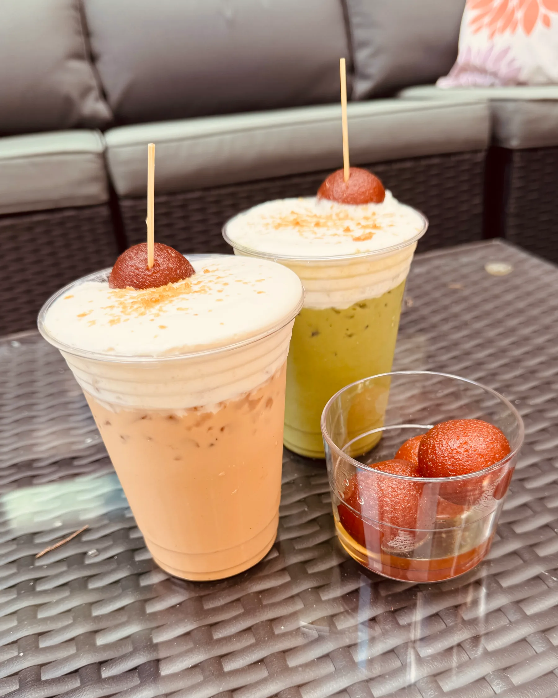 An iced latte and an iced matcha with pastry garnishes on the patio at Lee's Coffee