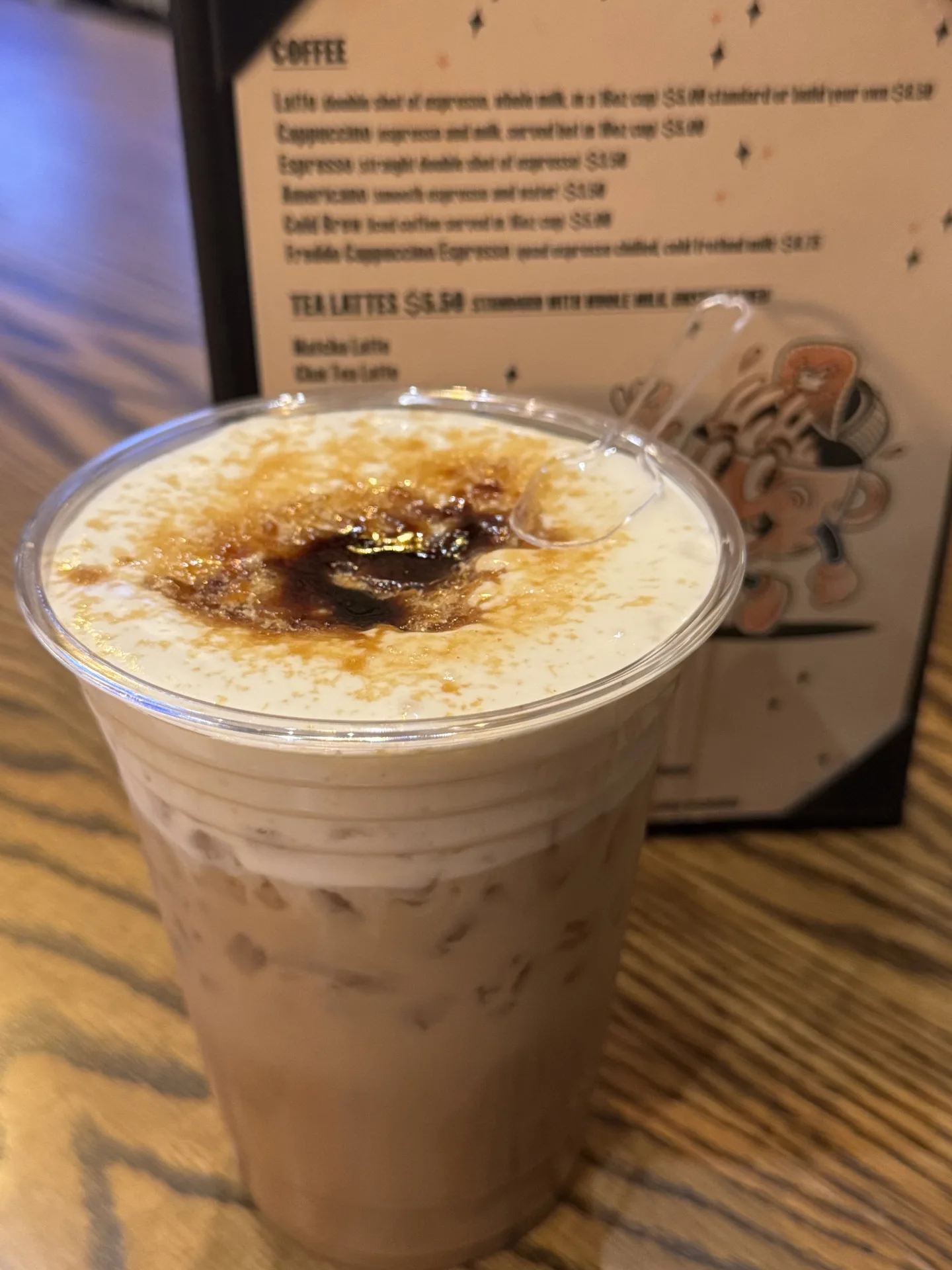 An iced coffee with cold foam in front of the Lee's coffee menu